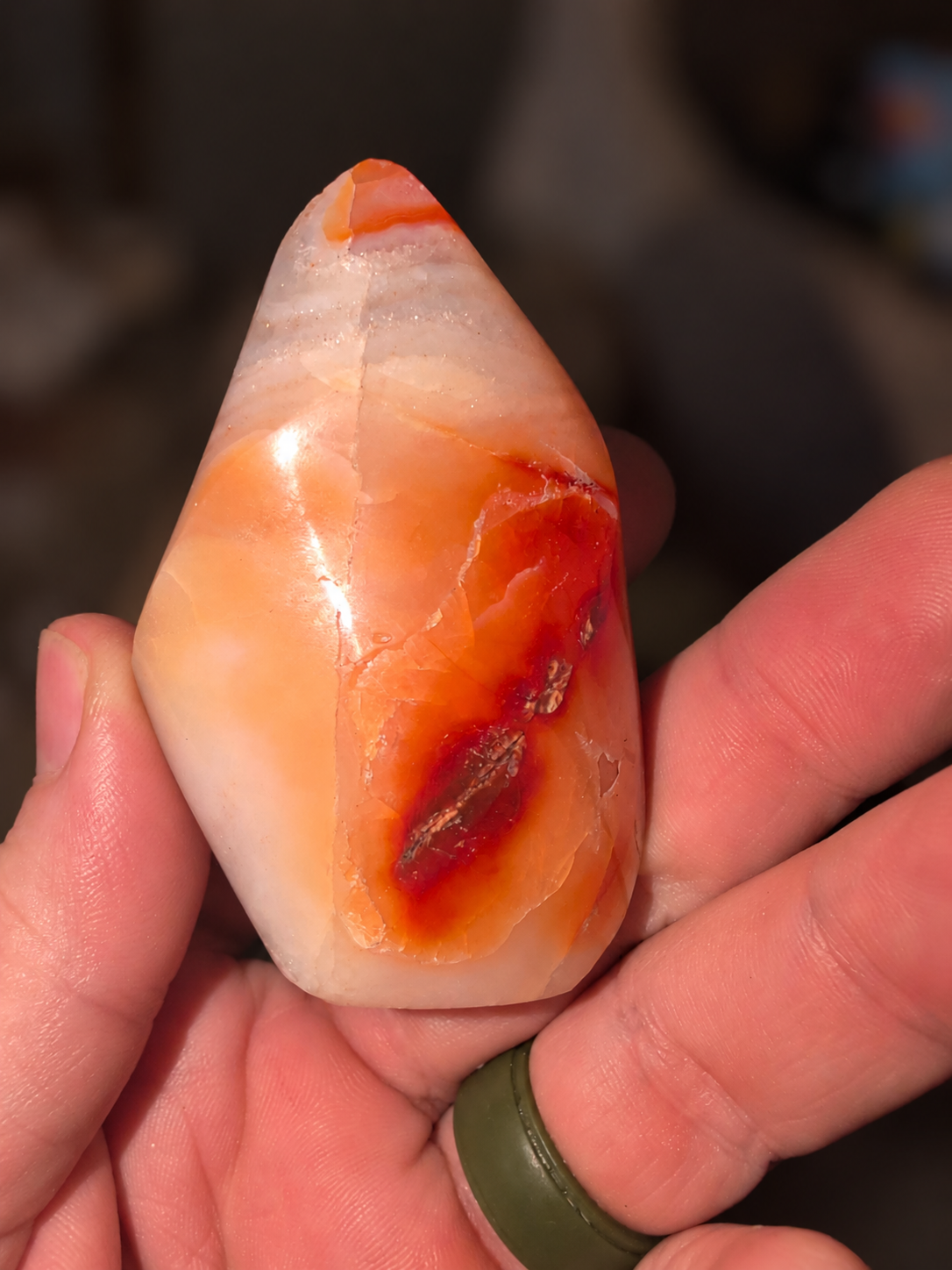 Orange polished freeform crystal held in a hand