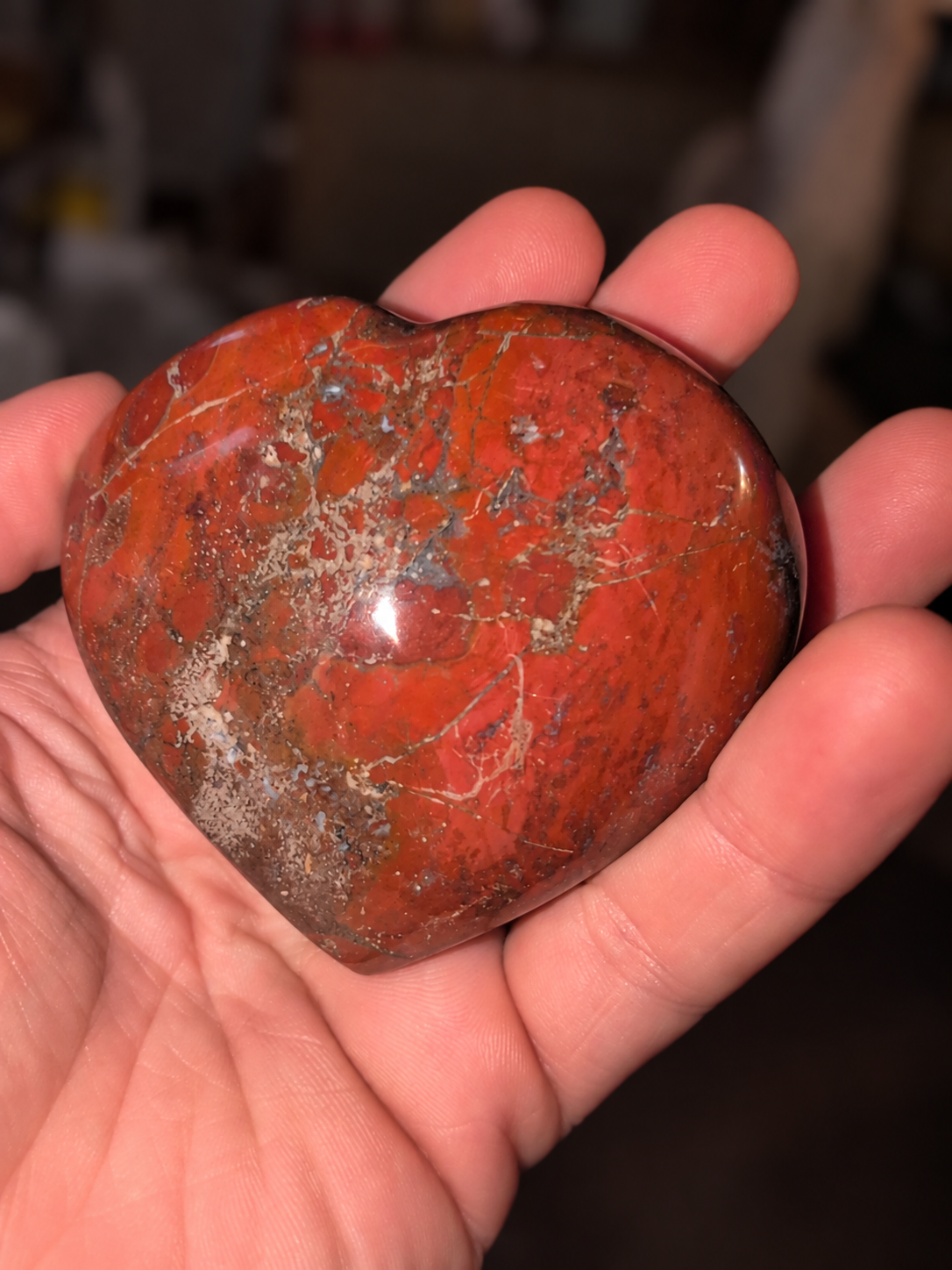 Polished red jasper heart held in a hand