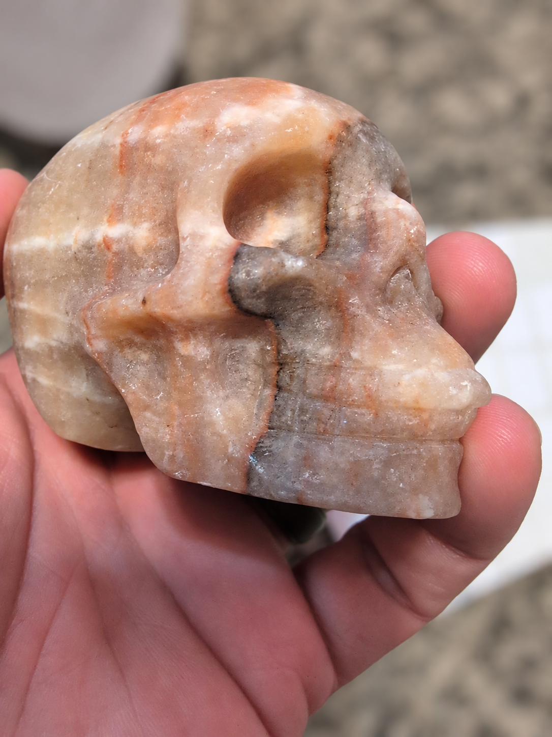 Carved multicolor stone skull held in a hand